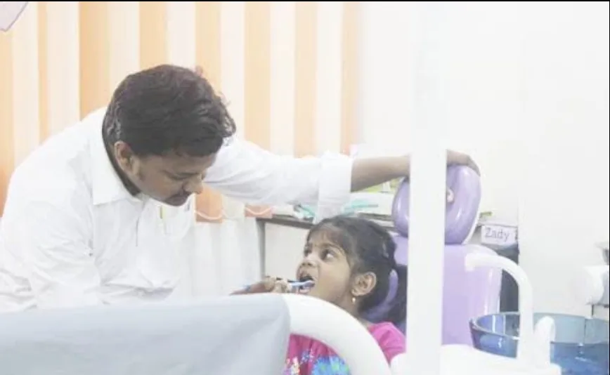 Dr. Satish Dolai teaching a young girl to brush at Bhanu Dental Care, Gajuwaka