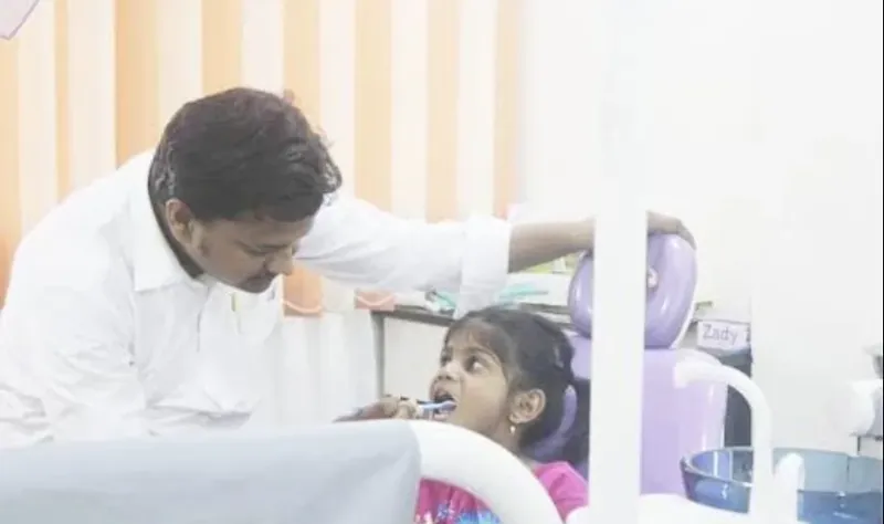 Dr. Satish Dolai teaching a young girl to brush at Bhanu Dental Care, Gajuwaka